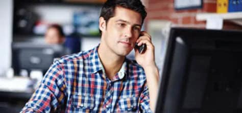 Image of man talking on the phone and looking at computer