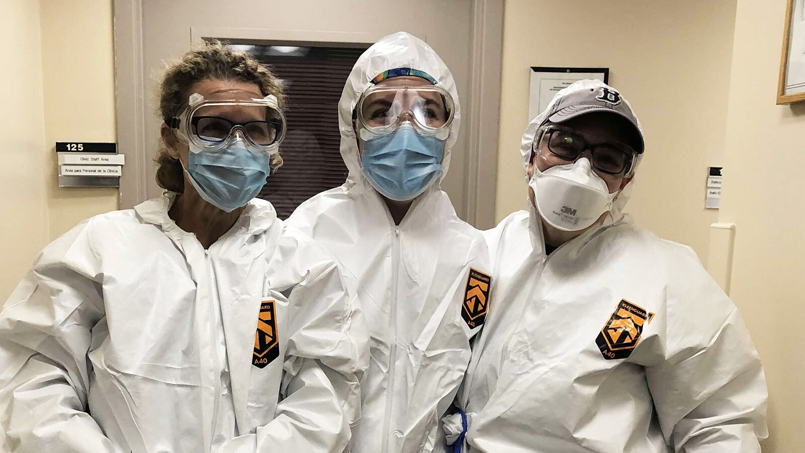 Three individuals in PPE 'smiling' to camera