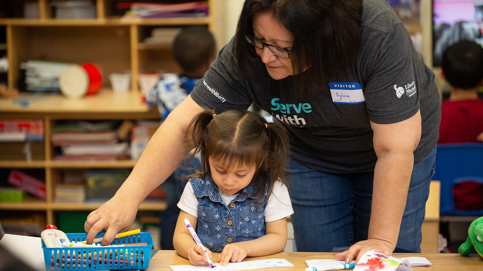 Liberty Mutual Serve Volunteer helping a young child color