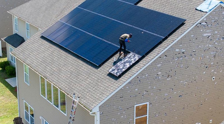 A person installing solar panels on a house