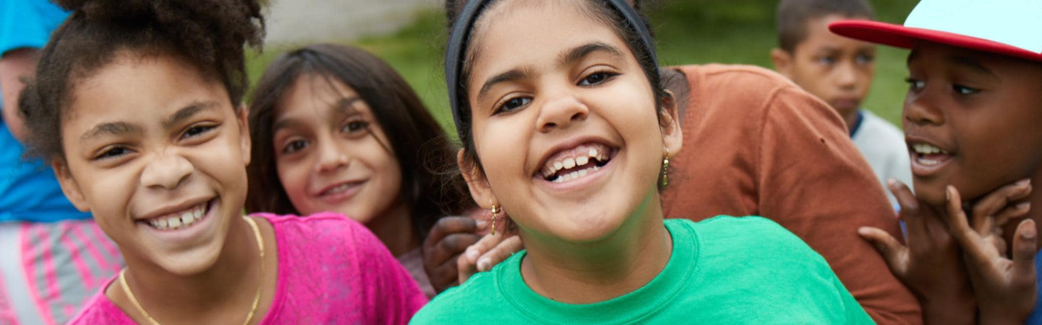 A group of children outside, playing and smiling to camera