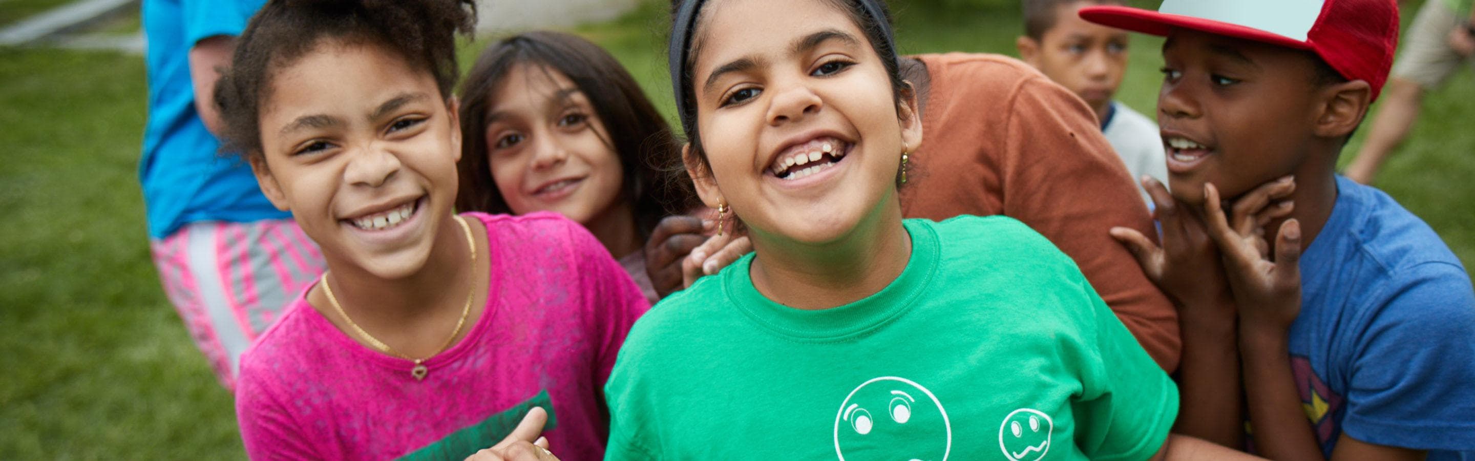A group of kids playing outside and smiling to camera