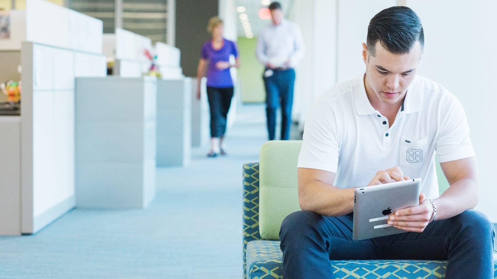 Male employee sitting down and doing work on a tablet