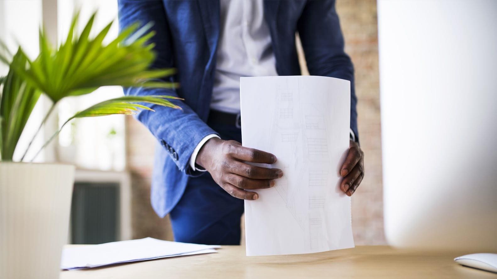 Someone standing behind a desk holding a printed report