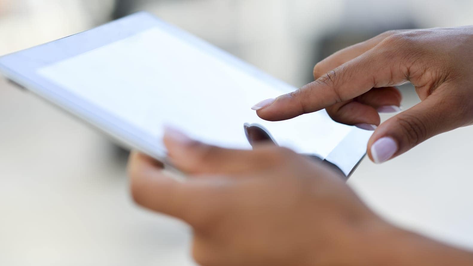 Close up of a person holding and using a tablet 