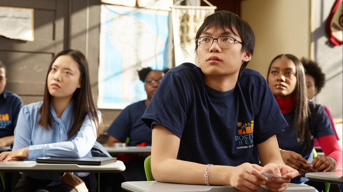 (slide 1 of 7) Diverse group of teenager in classroom setting, listening to speaker. 