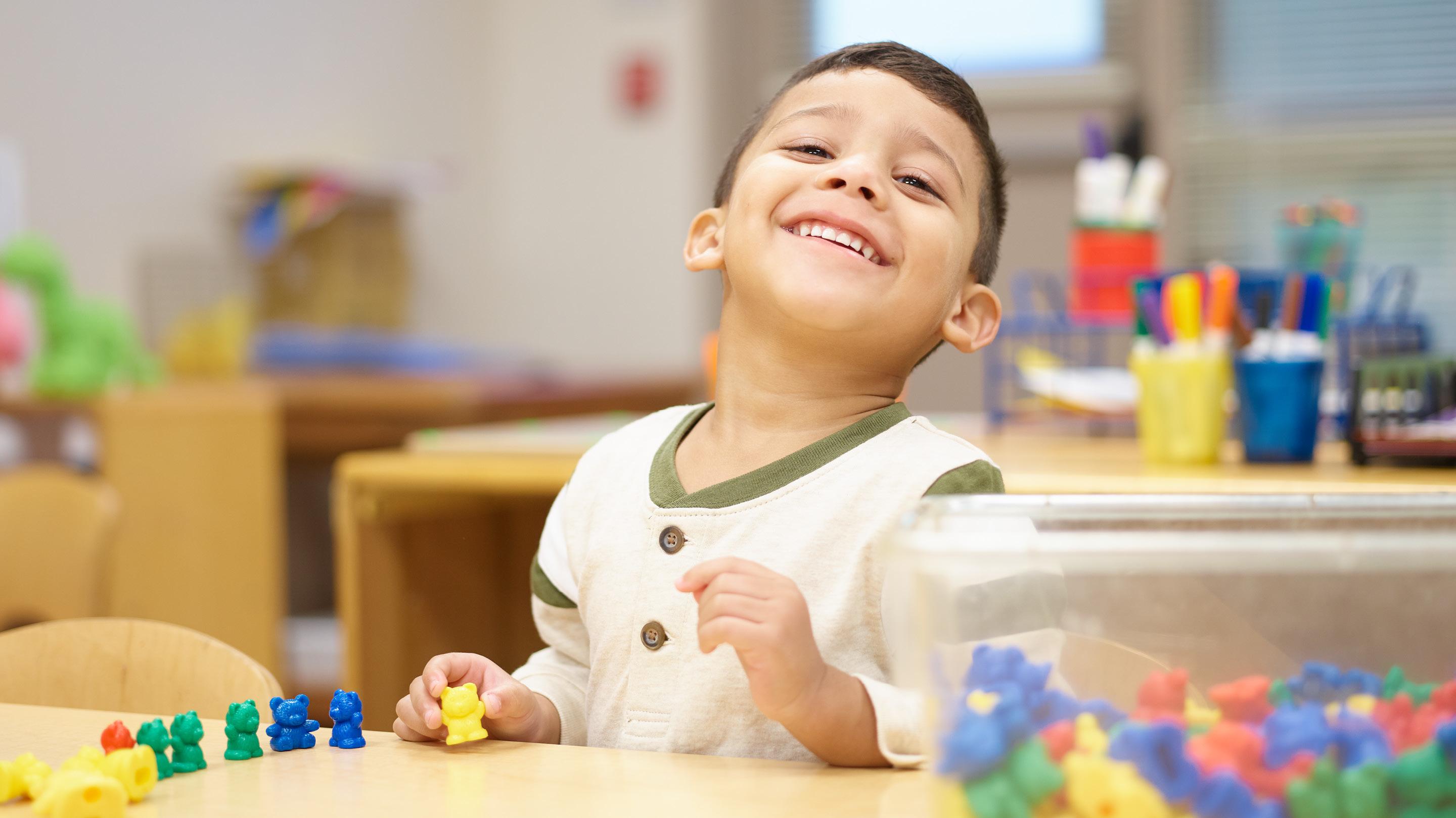 Young boy playing with mini plastic bears in a classroom
