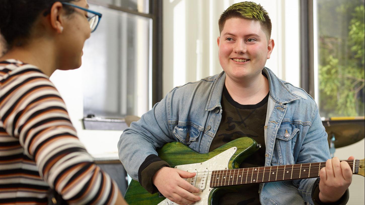 (slide 5 of 7) Teens siting, playing electric guitar . 