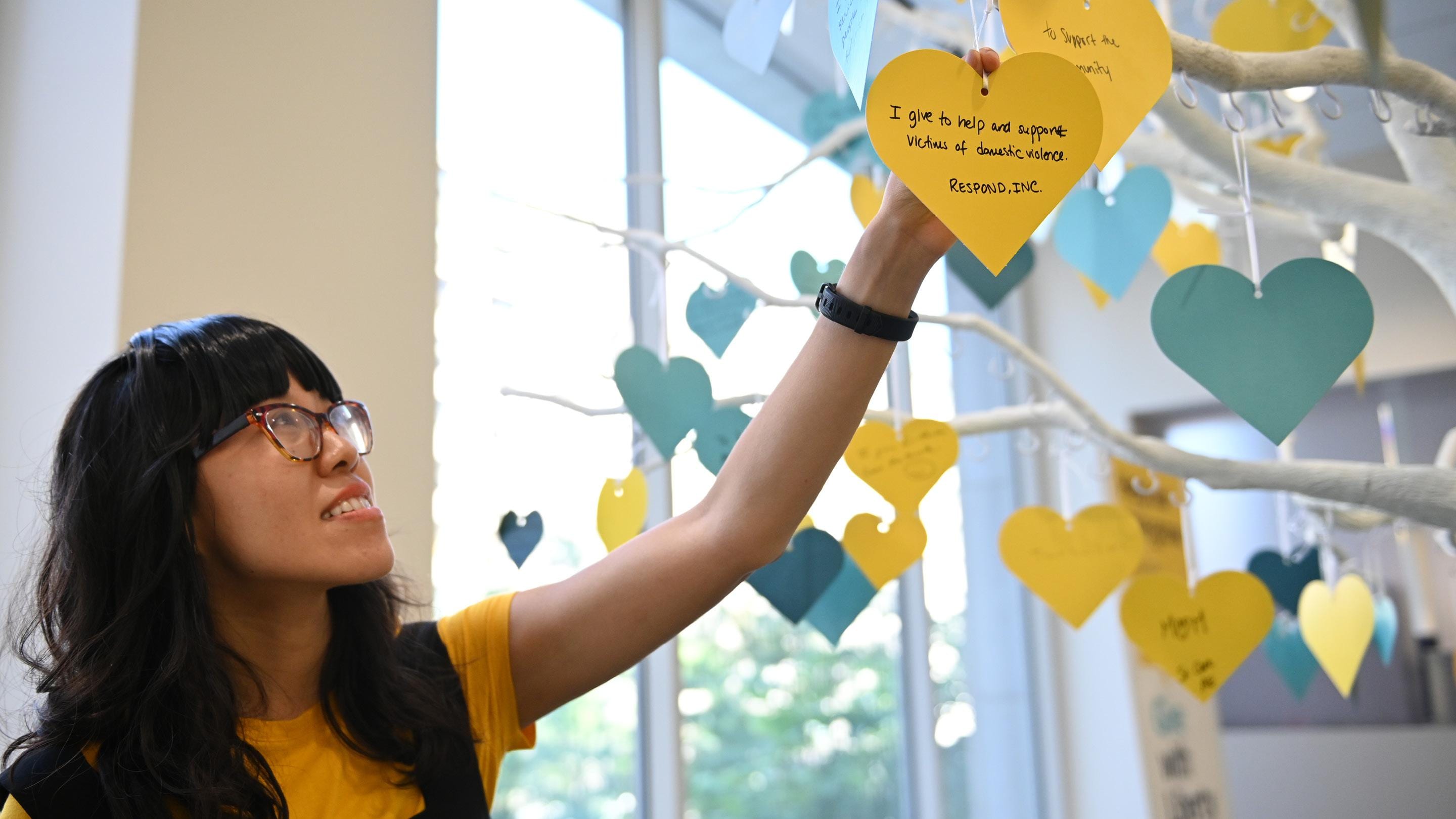 (slide 2 of 5) Liberty Mutual Employee adding a heart to the Give with Liberty Tree. 
