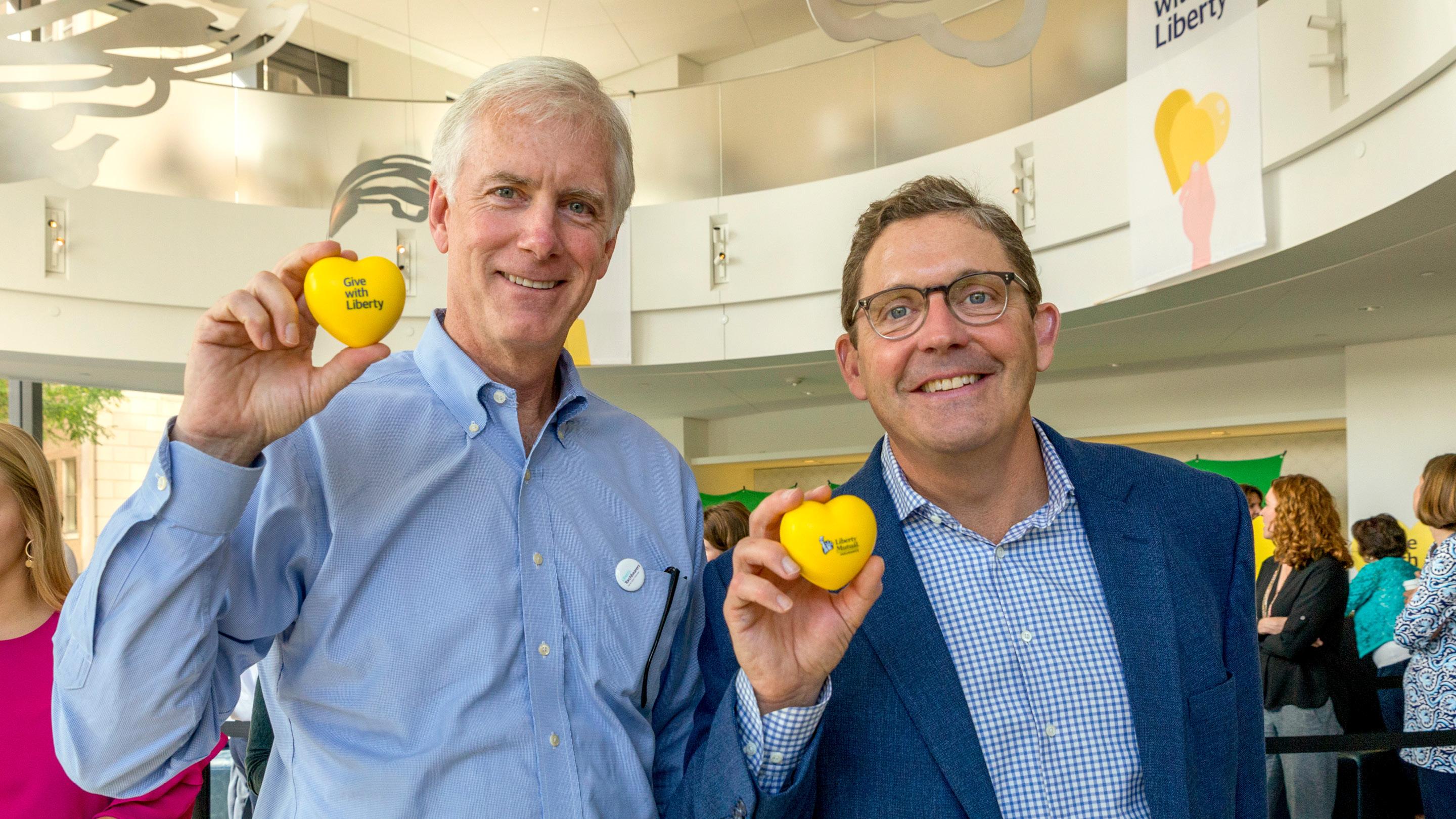 (slide 5 of 5) Image of Mark C. Touhey and Timothy M. Sweeney of Liberty Mutual holding up Give with Liberty heart-shaped stressballs. 