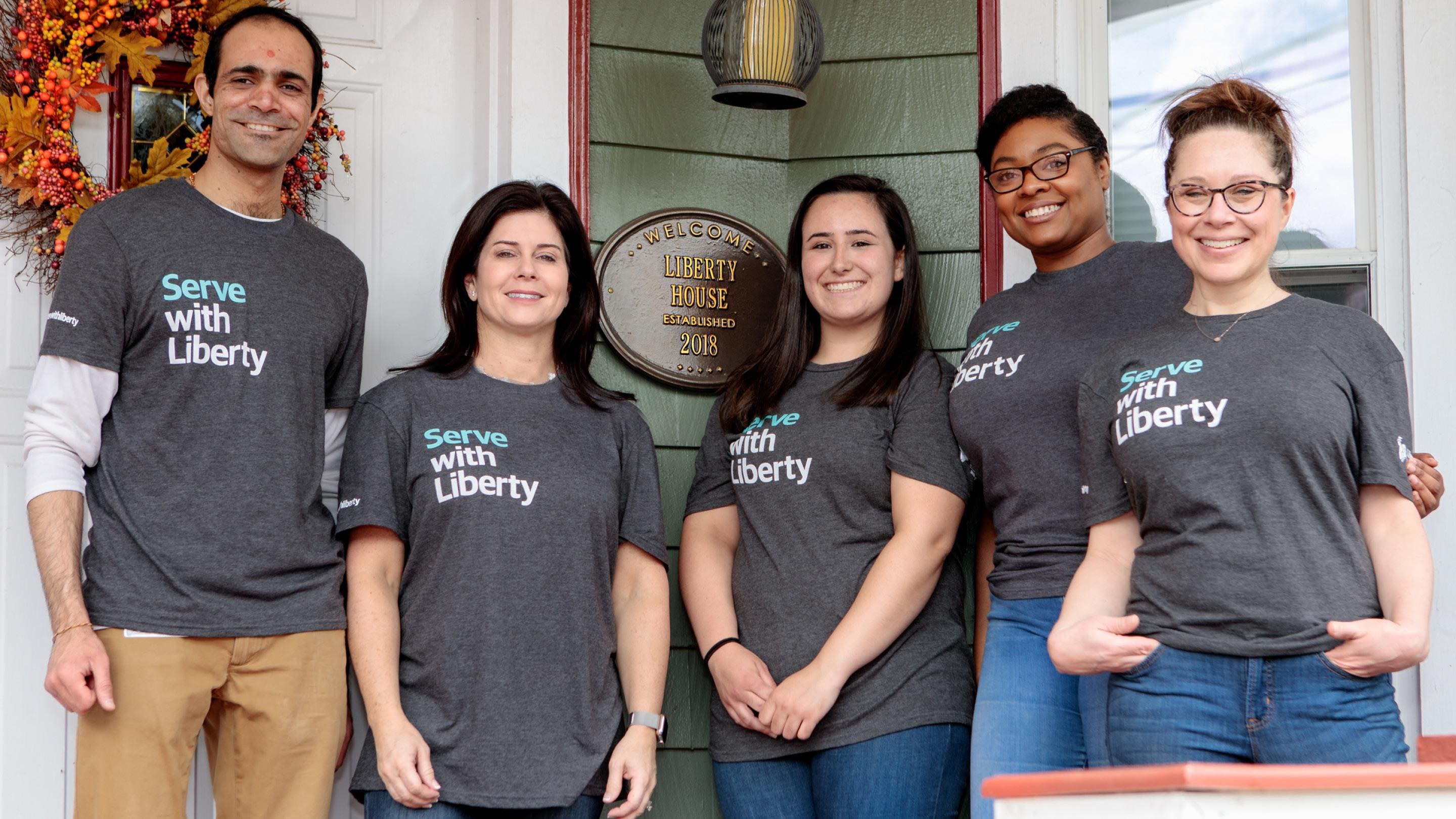 (slide 2 of 6) Liberty  Mutual Employees posing in Serve with Liberty shirts. 