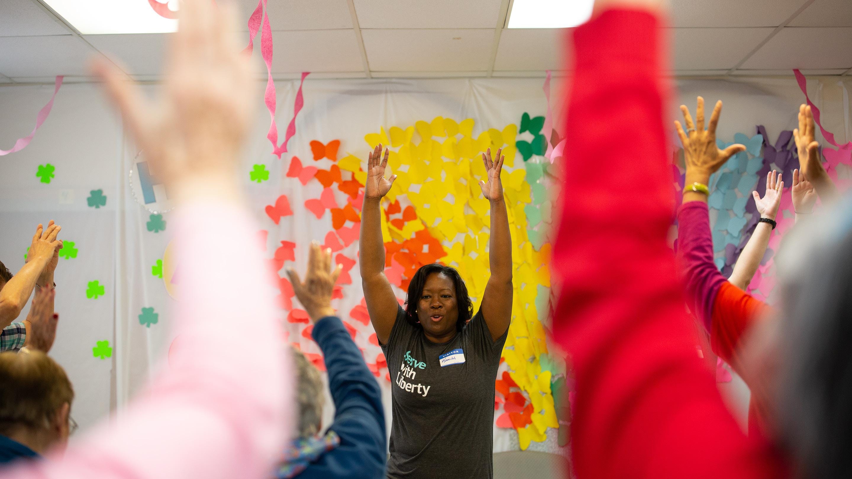 (slide 1 of 6) People raising their hands above their head stretching. 