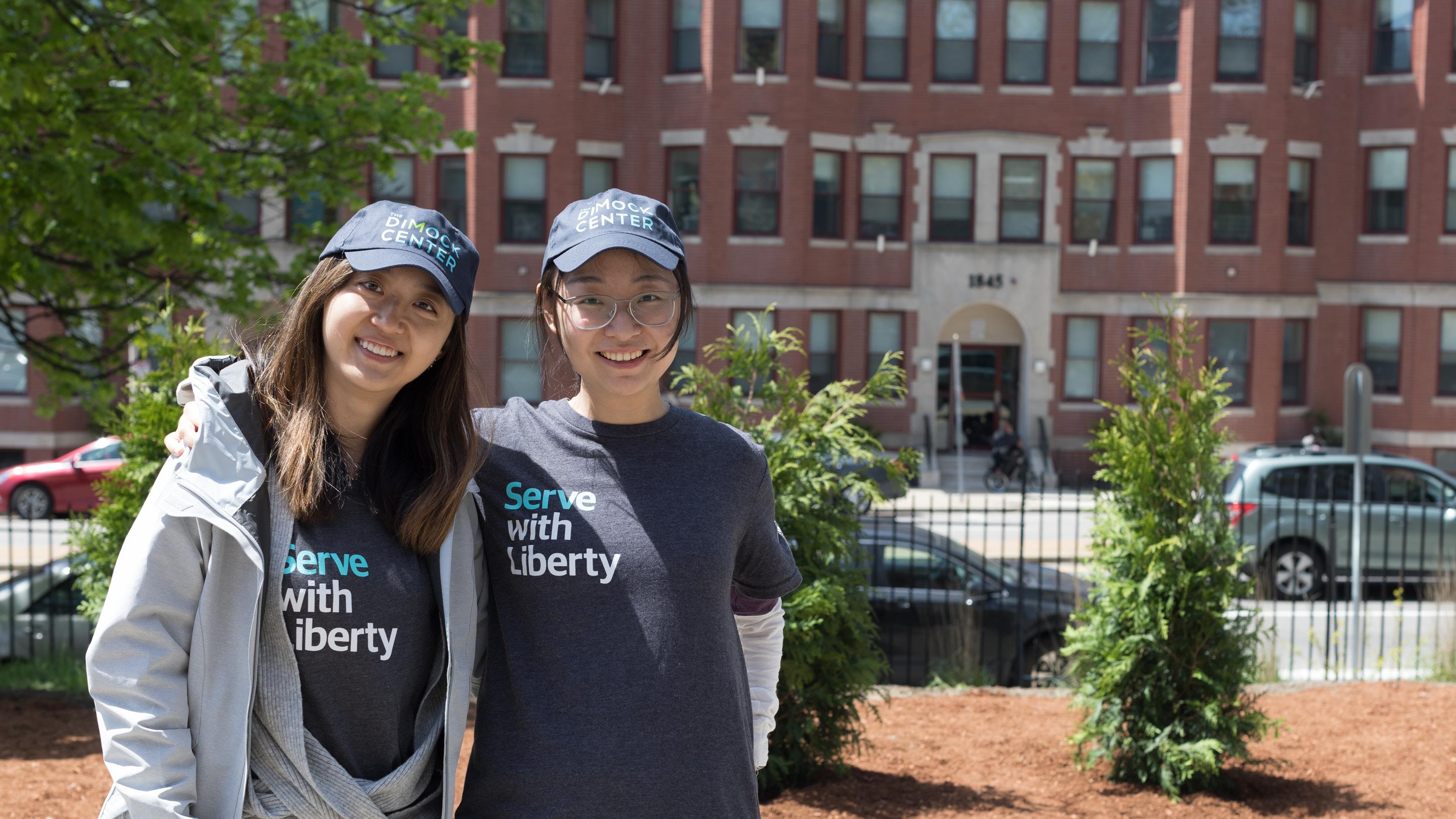 (slide 5 of 6) Two women wearing with Serve with Liberty shirts smiling into camera. 