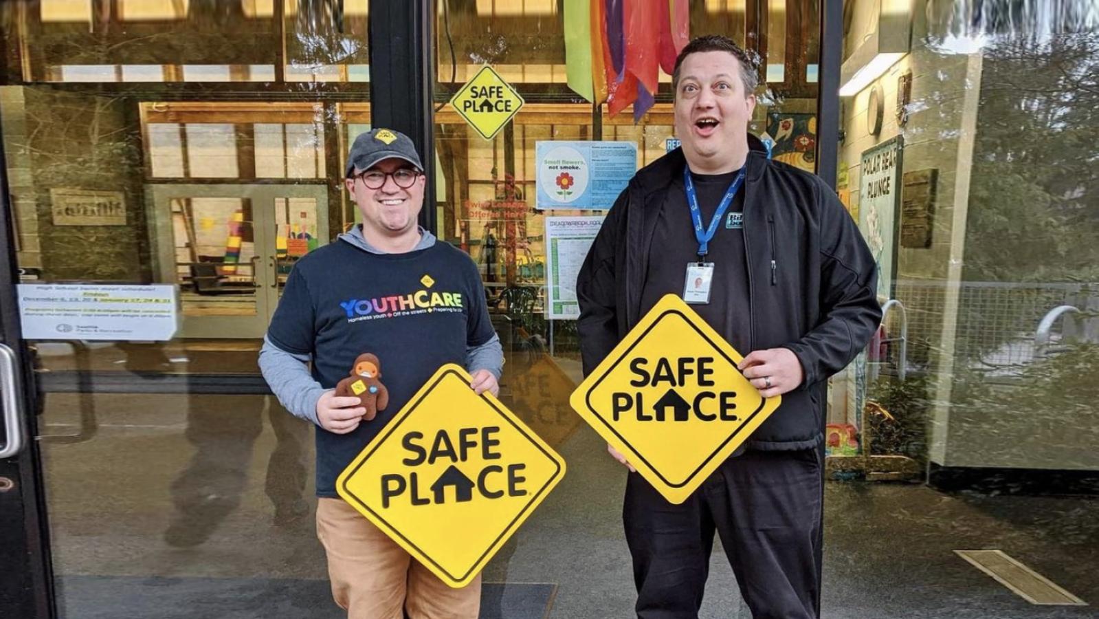 Two men from YouthCare nonprofit holding signs that read Safe Place 