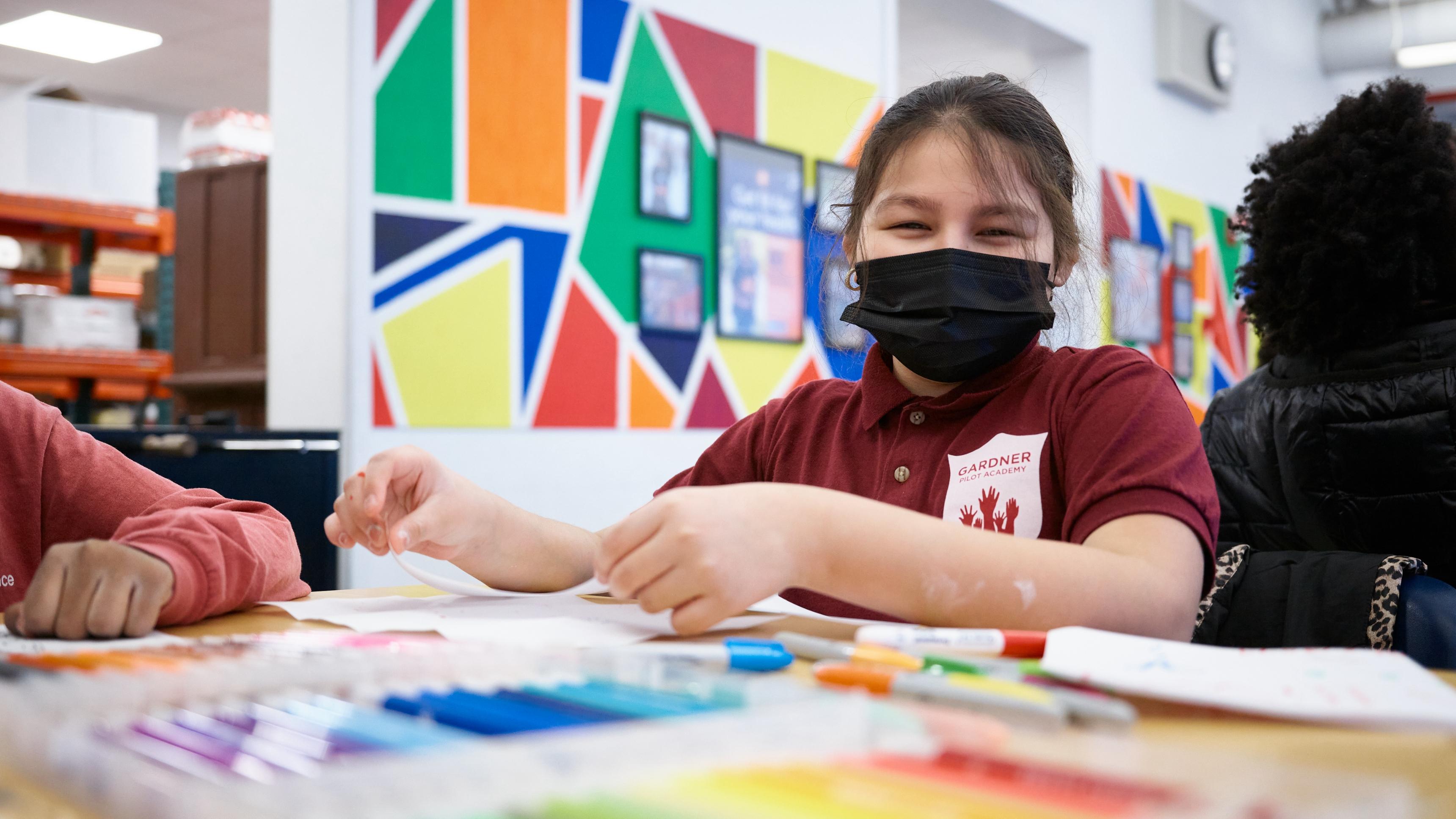 Young girl wearing a face mask, drawing in a classroom