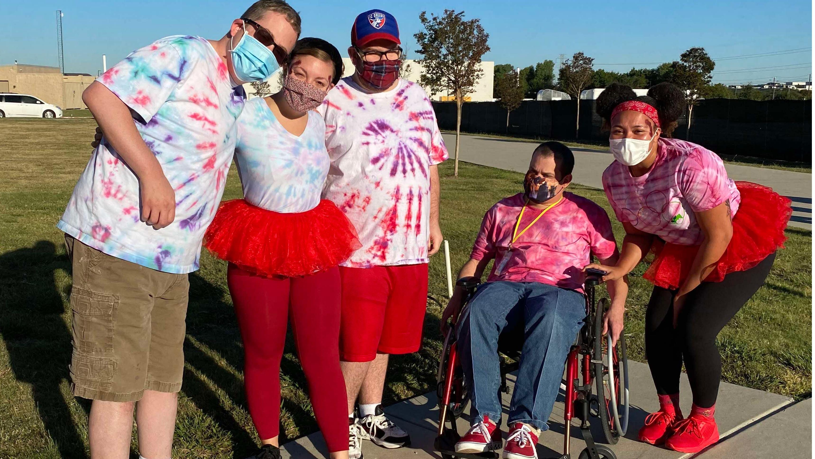 Young people wearing tie-dye and face masks posing to camera outdoors