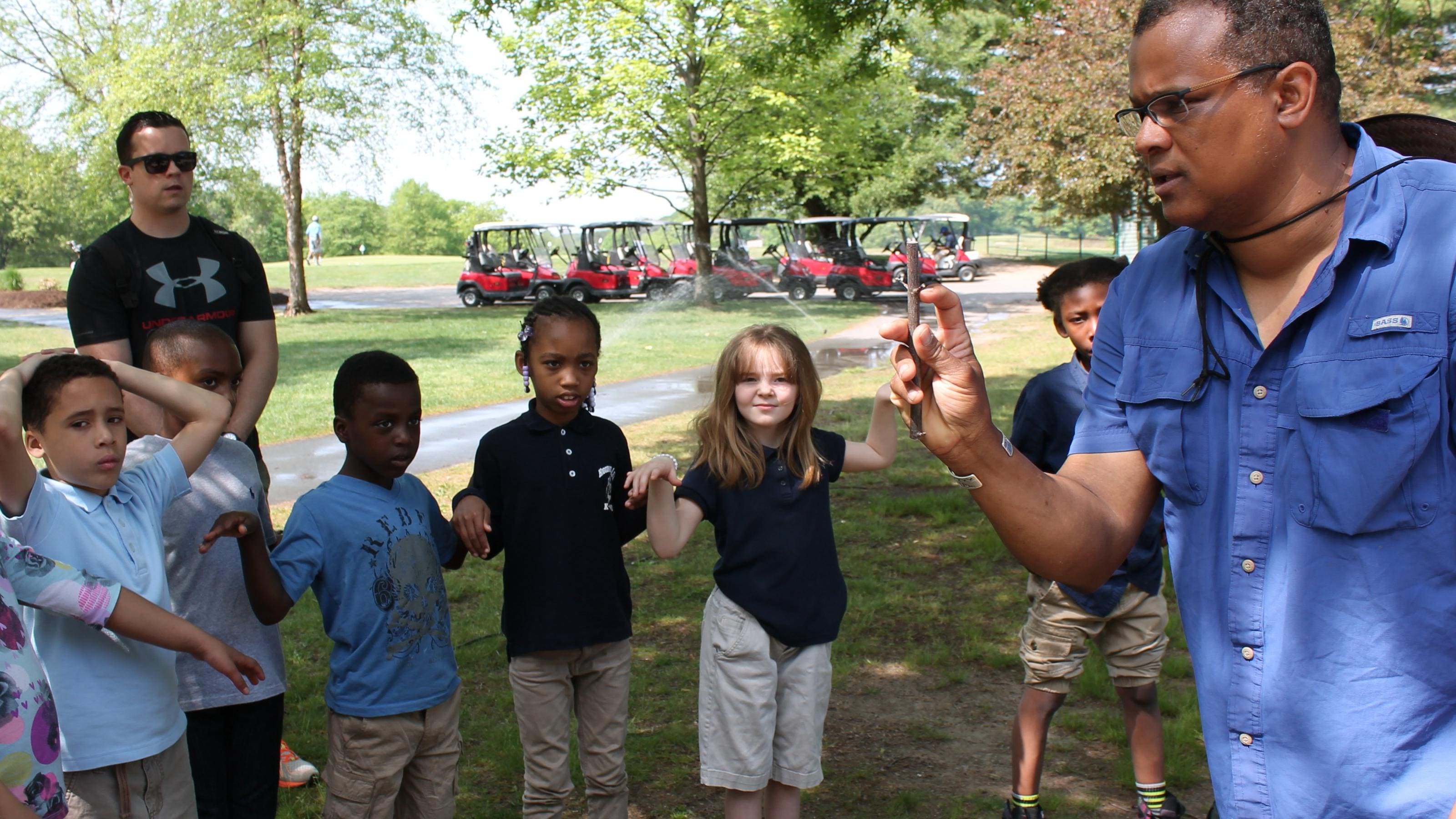 Young kids standing in a circle outdoors awaiting direction to play a game