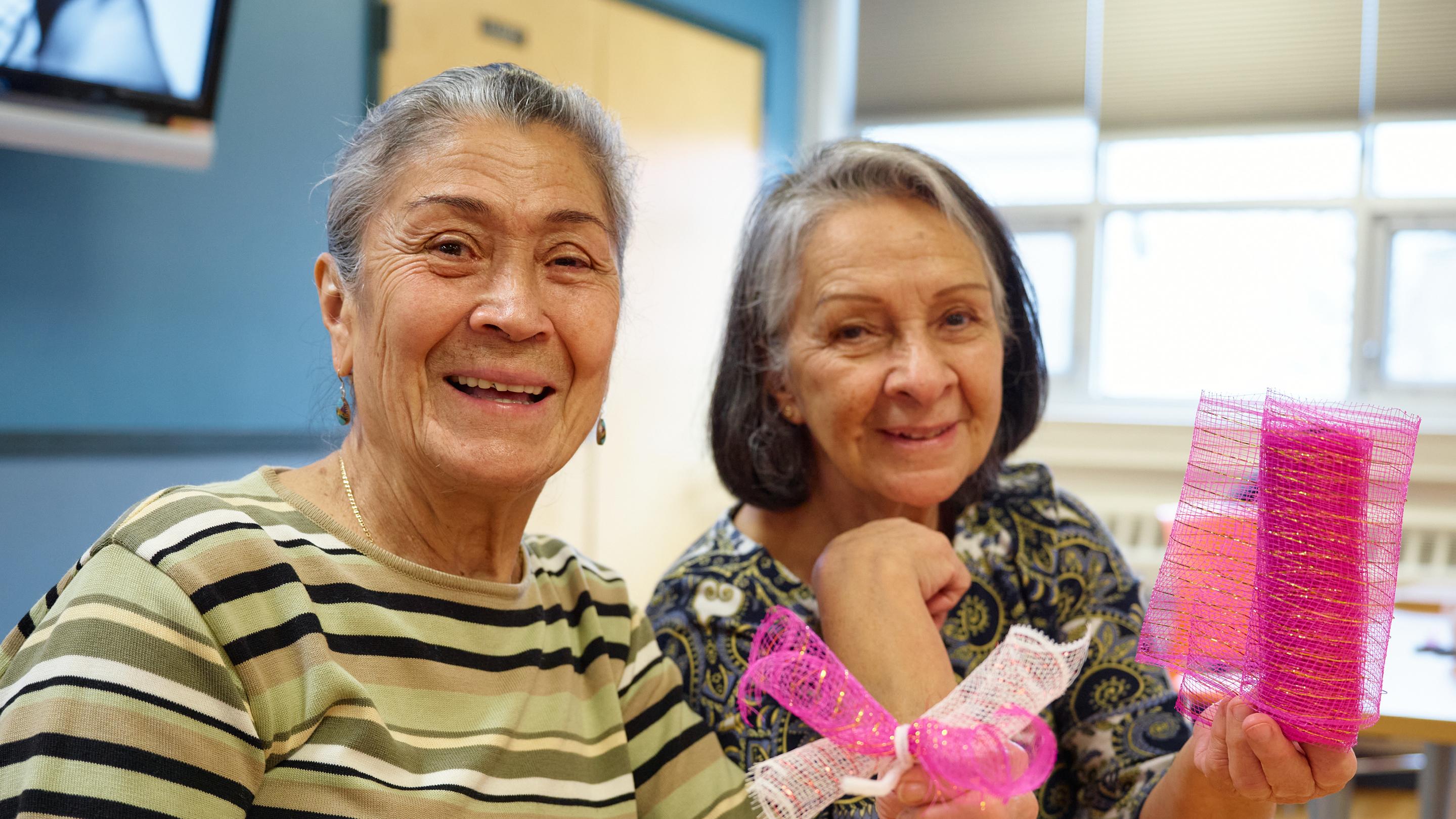 (slide 1 of 7) Two older women smiling to camera. 