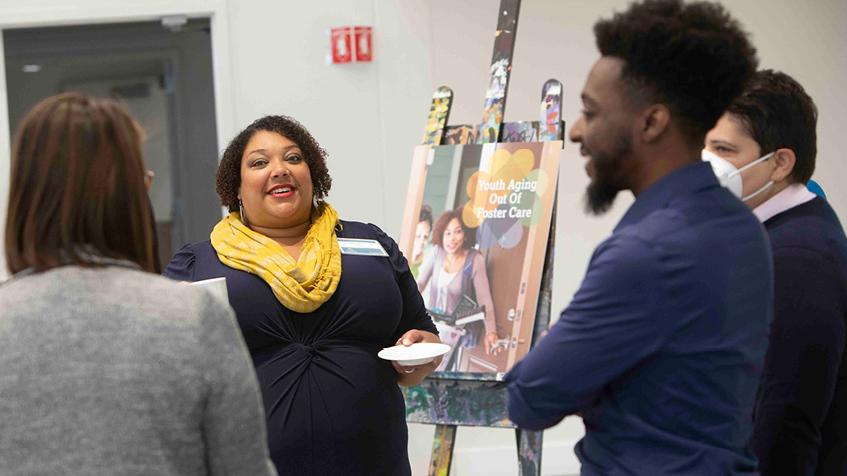 Group of people in front of an easel, one woman smiling to camera 