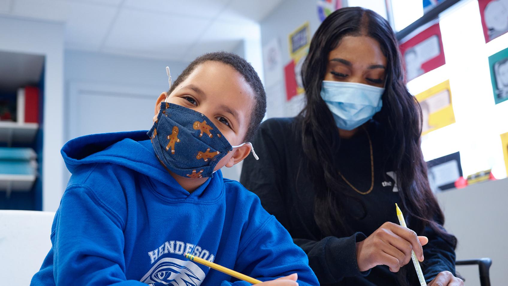 A masked adult and child smiling to camera