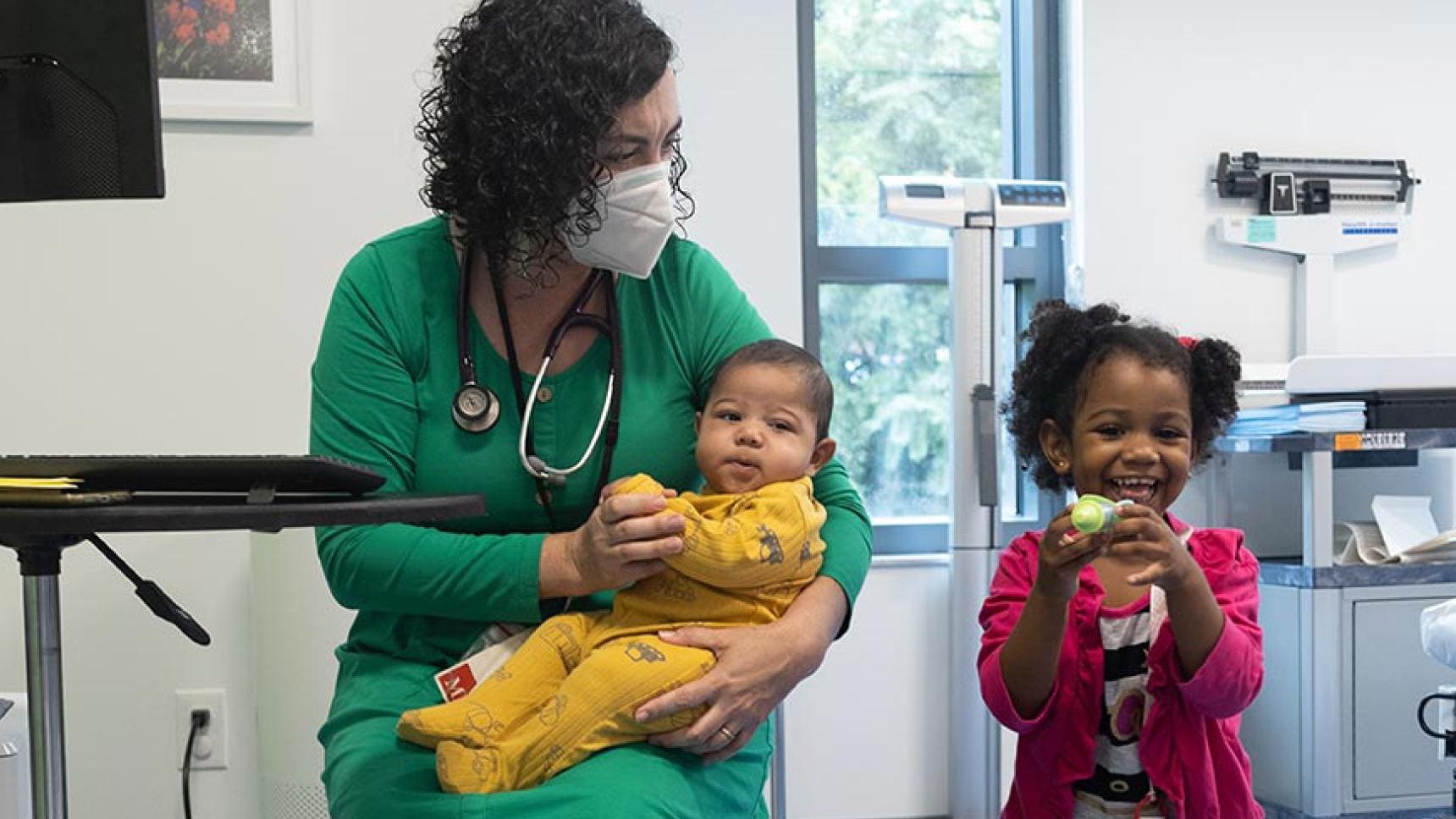 A medical professional working with two young, smiling children