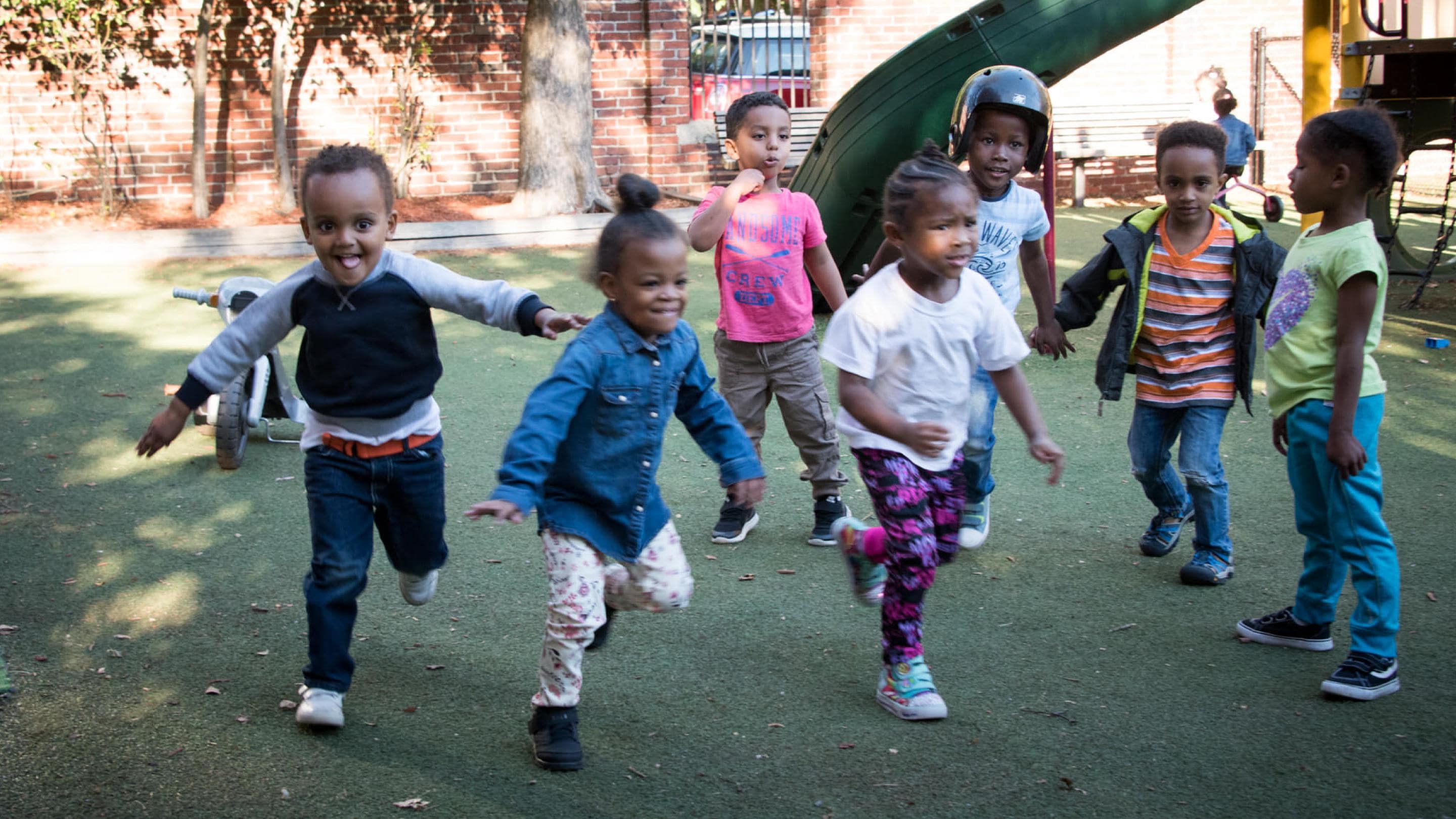 (slide 1 of 5) A group of children playing outside. 