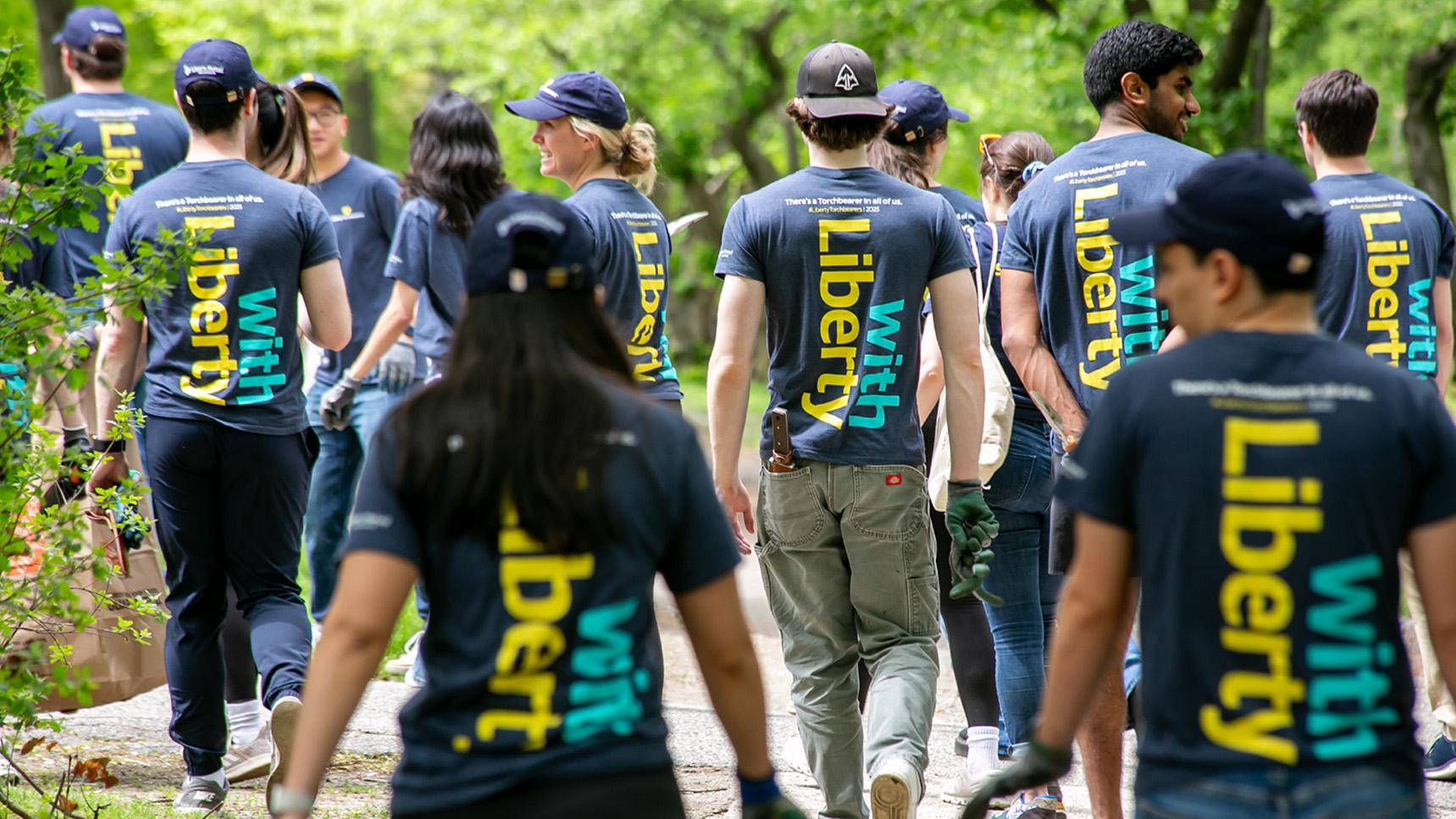 (slide 3 of 5) Group photo of LM Employees volunteering as part of Serve with Liberty - showing the back of their Serve volunteer shirts. 