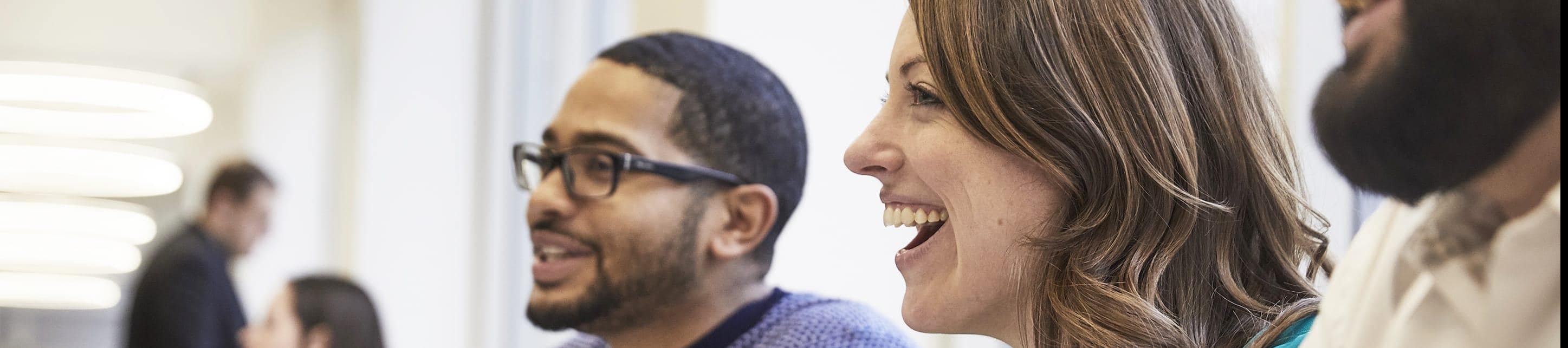 Close up of a male and a female employee smiling and talking in an open space