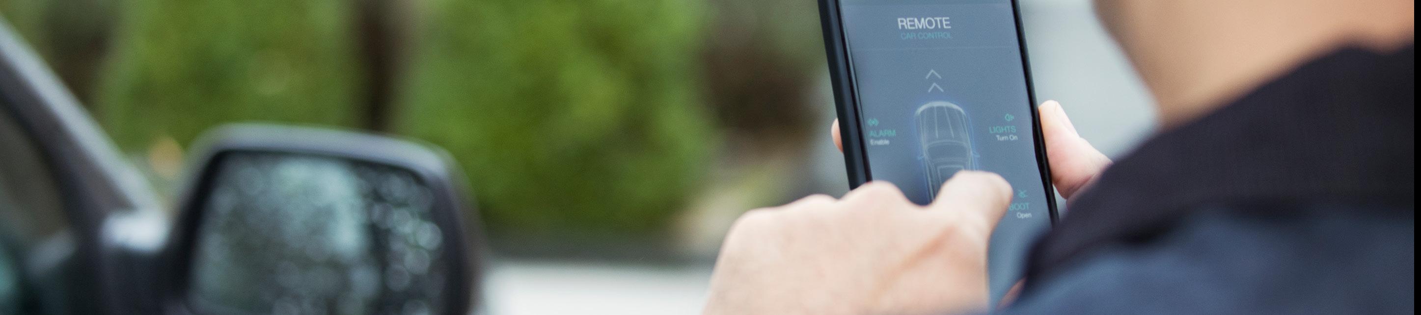 Focus image of someone using their smartphone outside while looking at a car