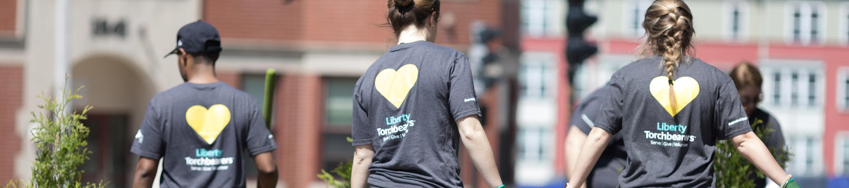 Three Liberty Mutual volunteers wearing Serve with Liberty shirts, outdoors