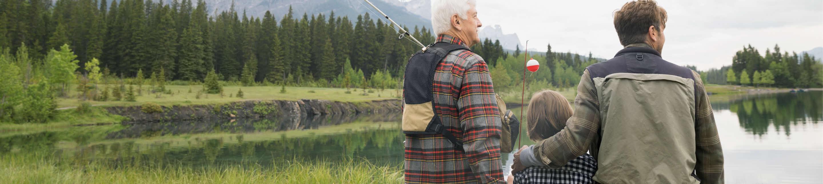 Three people standing by a lake after a day of fishing