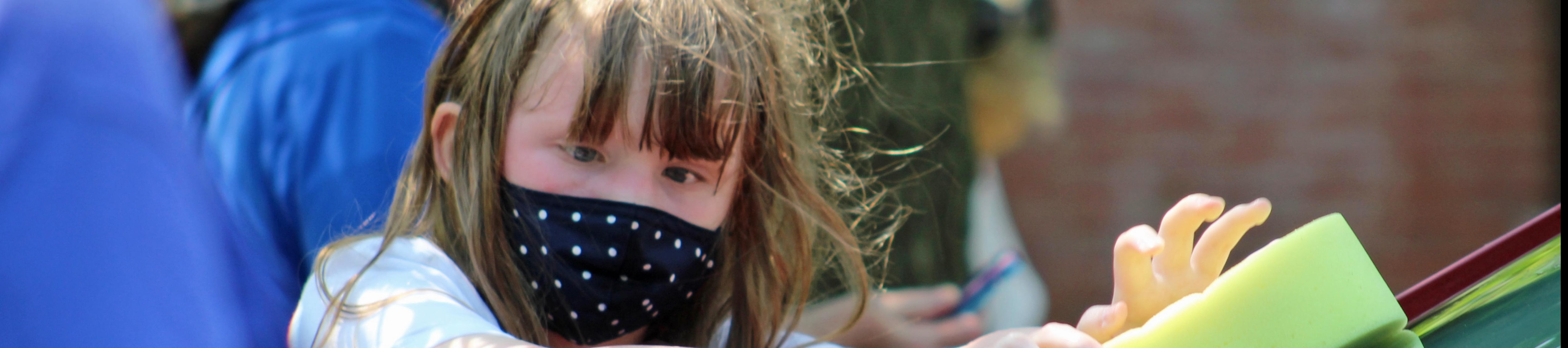Young girl in a face mask playing outdoors