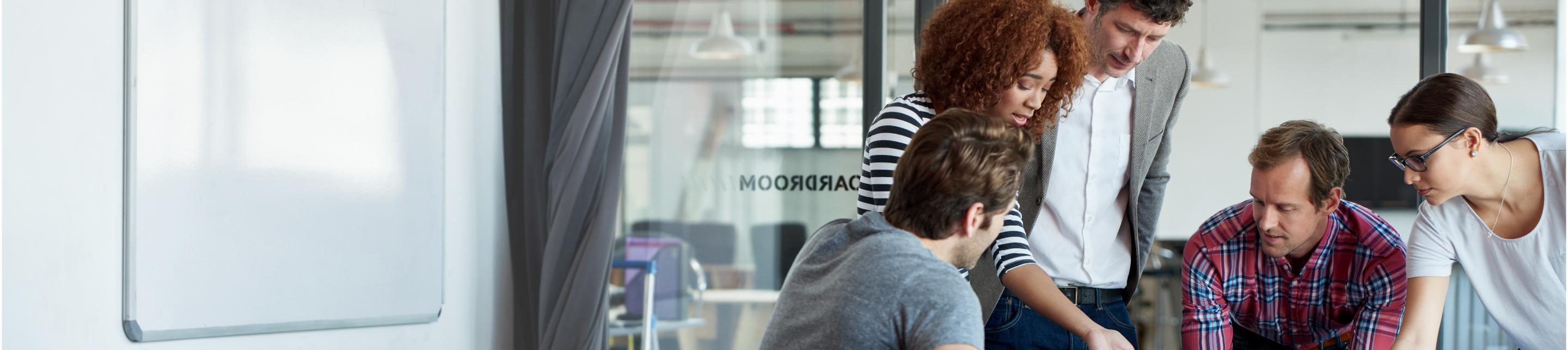 Group of people huddling around a table in an open office setting, chatting