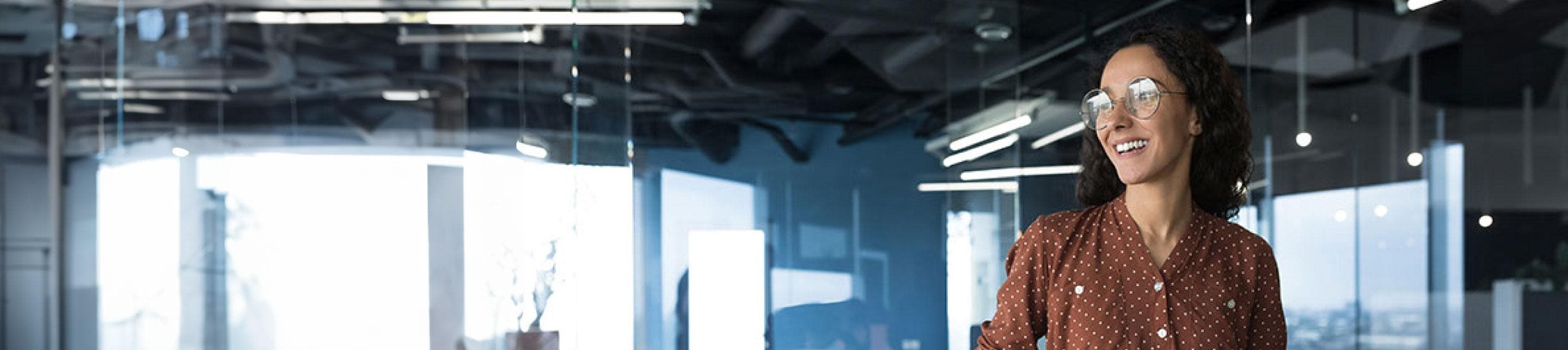 A woman in an airy office setting, smiling off camera