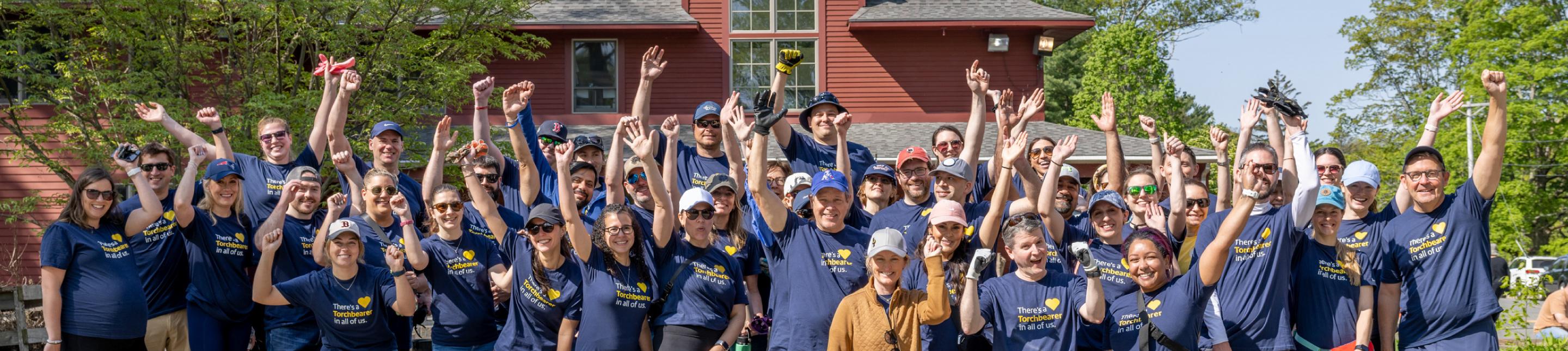 Group of LM employees volunteering at Serve with Liberty; smiling and cheering while they are photographed